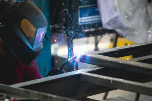 Welder in a protective helmet welding a steel frame during welding certification testing