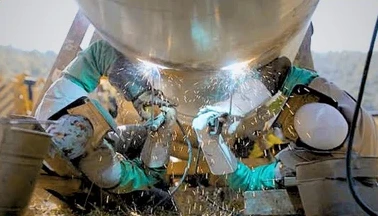 Welders performing weld testing on a large-diameter pipe